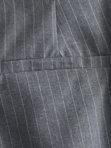 Macro shot of dark grey pinstripe fabric detail and pocket stitching on women's jacket