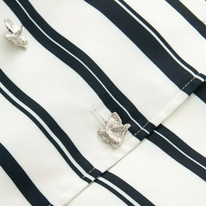 Macro shot of silver bird-shaped buttons on striped fabric of the short skirt set