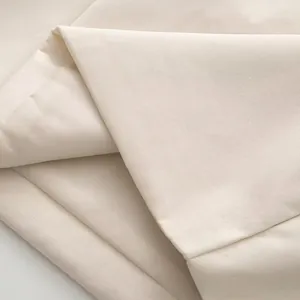 Gros plan sur le tissu crème de la robe avec détails en strass et texture tissée
