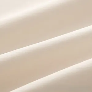 Vue macro détaillée du tissu textile beige avec des drapés souples et une texture tissée