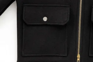 Detailed macro view of a black wool jacket featuring a silver metal zipper and pocket flap