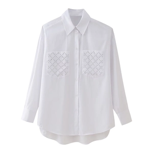 Close-up of white button-up shirt featuring rhinestone studded front pockets and a curved hem