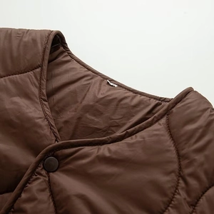Macro detail of dark brown quilted jacket featuring round stitching and snap button