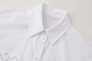 Close-up of white collar shirt featuring silver stud details on pocket and cotton texture