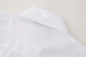 Close-up of white shirt collar and shoulder stitching with subtle rivet decorations