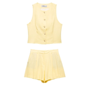 Detail of pale yellow two-piece set featuring amber buttons and linen-textured fabric