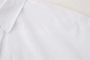 Detail view of neatly stitched shoulder seams and collar on a white rivet shirt