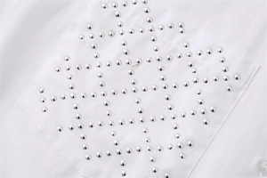 Close-up of snowflake pattern made of silver rivets on white shirt pocket