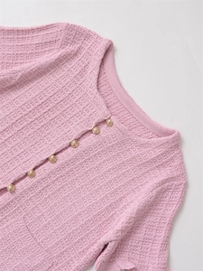 Close-up of pink knit cardigan with waffle texture and golden embossed buttons