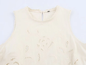 Detail of cream sleeveless top with floral embroidery, eyelet lace, and scalloped neck