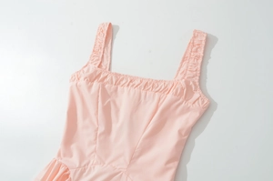 Detailed view of pink square neck dress featuring ruffled shoulder straps and woven fabric