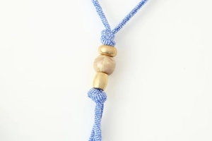 Detailed macro of blue and white woven cord with marble resin bead and gold accents