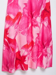 Détail d'un imprimé floral rouge et rose sur tissu satiné léger avec des bords ourlés de qualité