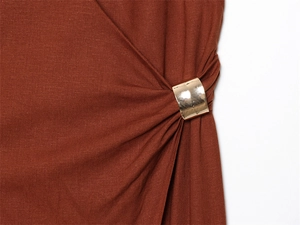 Détail de robe midi en lin caramel montrant une boucle dorée carrée avec de légers plis
