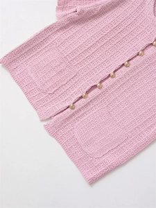 Detail of pink knit cardigan featuring ornate gold embossed buttons and textured pockets