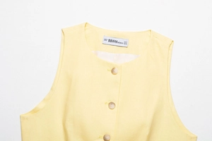 Detail of light yellow sleeveless vest showing cotton linen texture and button closure