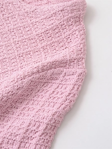 Close-up of pink knit sweater showing detailed waffle texture and honeycomb stitch pattern