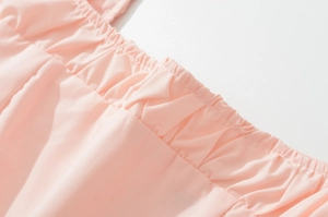 Detailed close-up of pink woven dress featuring elegant pleats and refined stitching