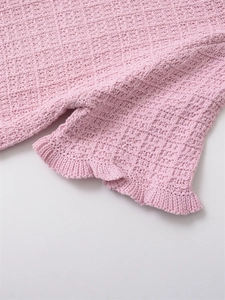 Detailed macro view of pink waffle knit texture and delicate ruffle hem on women's top