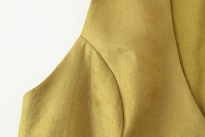 Vista macro dettagliata del tessuto satinato giallo senape con cuciture e trama di lusso