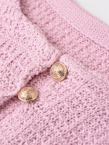 Macro shot of pink knit fabric texture with ornate vintage gold crest buttons
