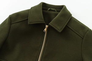 Detail of dark green wool jacket featuring a high-quality gold metal zipper and lapel