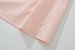 Close-up of light pink woven fabric showing fine single-needle stitching and texture