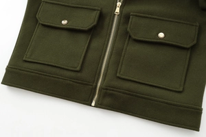 Close-up of forest green wool jacket with golden zipper and buttoned flap pockets