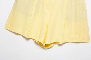 Detailed view of pale yellow linen high-waisted shorts with visible woven fabric texture