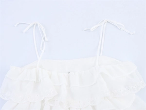Detail eines weißen Camisole-Tops mit Rüschenschichten und feiner Lochstickerei