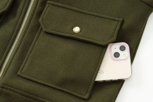 Close-up of dark green wool jacket featuring a large pocket with golden button and zipper
