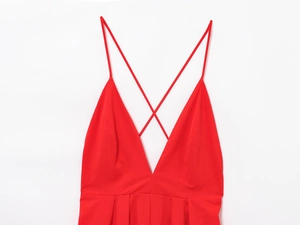 Detail of red backless V-neck dress featuring thin crisscross straps and pleated bust line