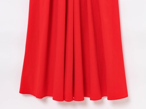Close-up of vibrant red dress hemline featuring vertical pleats and neat stitching detail