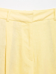 Detailed view of pale yellow linen trousers waist with belt loops and neat stitching