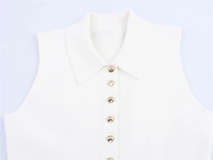 Détail d'un gilet en tricot blanc avec col polo et boutons décoratifs en métal doré