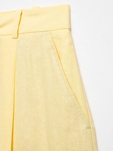 Detailed close-up of light yellow trousers showing fabric texture, belt loops and pockets