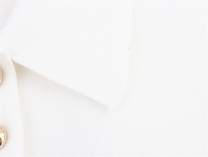 Détail de polo en maille blanche avec d'élégantes touches de boutons dorés arrondis