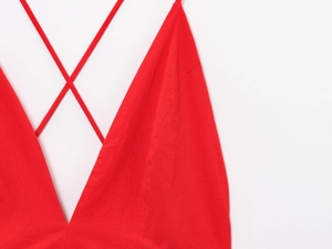 Detailed view of red V-neck dress featuring delicate criss-cross straps and fine texture