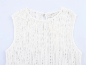 Détail d'un haut en tricot blanc sans manches avec motifs ajourés et bouton au dos du col