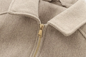 Detailed macro view of beige wool blend jacket with high-quality gold metal zipper hardware