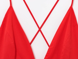 Close-up of bright red V-neck dress featuring criss-cross thin straps and textured fabric
