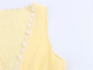 Detailed view of the light yellow V-neckline featuring delicate white floral lace trim