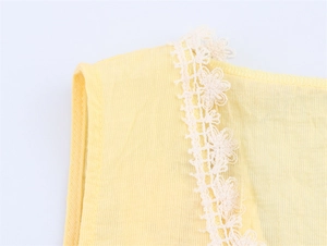 Detailed close-up of ribbed fabric texture with floral lace trim on a yellow tank top