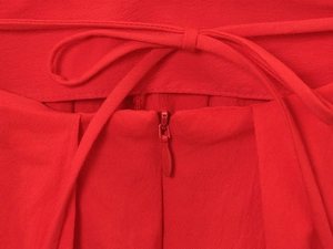 Close-up of bright red fabric texture with a concealed zipper and matching waist tie