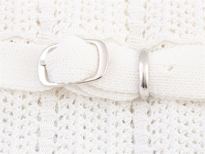 Détail de la robe en crochet blanc avec ceinture assortie et boucle en métal argenté en forme de D