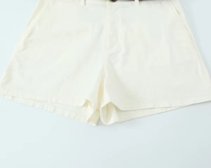Close-up of cream pleated shorts with slant pockets and high-quality cotton fabric