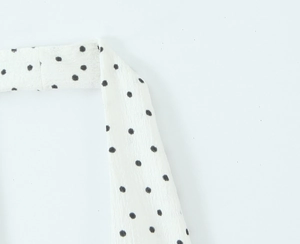 Détail du tissu en mousseline blanche à pois noirs avec une texture crêpe fine