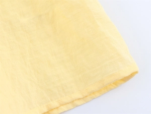 Close-up of light yellow sleeveless top featuring delicate lace trim and neat hem stitch