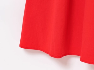 Close-up of precision hem stitching on the vibrant red cotton fabric dress hemline