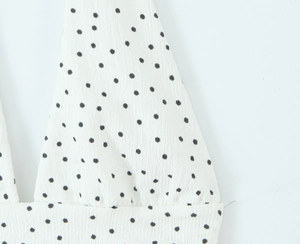 Gros plan sur un tissu en mousseline blanche avec un élégant motif à pois noirs fins